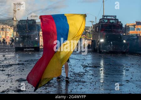 Bogota, Colombia. 21st June, 2021. A demonstrator waves a Colombian flah in the middle of two armored riot tanks as clashes between demonstratros and Colombia's riot police erupt anti-government protest raise in Bogota Colombia against the government of president Ivan Duque, inequalities and abuse of authority by police. Credit: Long Visual Press/Alamy Live News Stock Photo