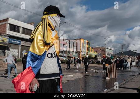 Bogota, Colombia. 21st June, 2021. A demonstrator uses a Colombian flag as a cape as clashes between demonstratros and Colombia's riot police erupt anti-government protest raise in Bogota Colombia against the government of president Ivan Duque, inequalities and abuse of authority by police. Credit: Long Visual Press/Alamy Live News Stock Photo