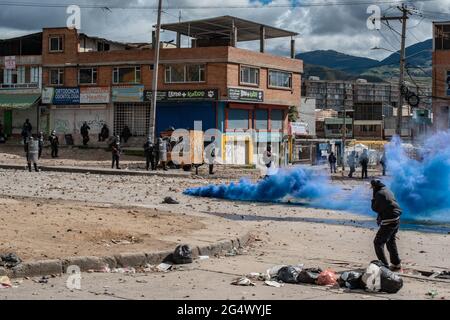 Bogota, Colombia. 21st June, 2021. A blue smoke tear gas grenade blows as clashes between demonstratros and Colombia's riot police erupt anti-government protest raise in Bogota Colombia against the government of president Ivan Duque, inequalities and abuse of authority by police. Credit: Long Visual Press/Alamy Live News Stock Photo