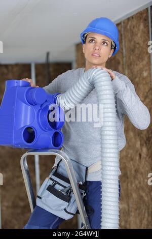 female worker fitting ventilation system Stock Photo