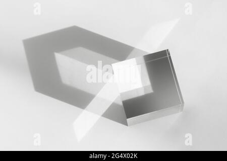 Glass transparent cube with sun reflection, geometric stand for cosmetic, light and shadow on white. Acrylic block, podium for product presentation Stock Photo