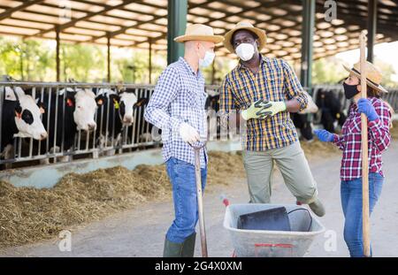 Farmers in protective masks discussing working process near stall Stock Photo