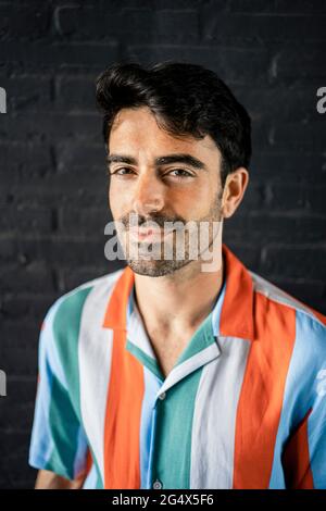 Smiling man with black hair in multi colored striped shirt Stock Photo