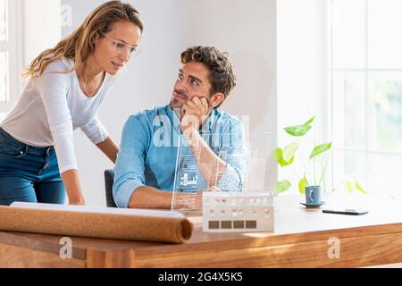 Mid adult colleagues working over transparent digital tablet in office Stock Photo