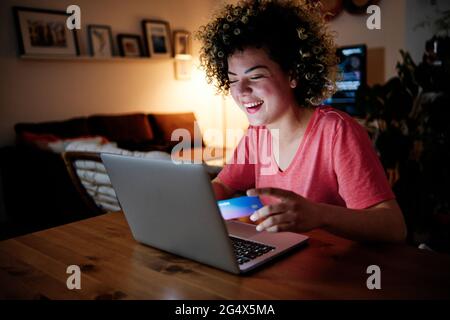 Cheerful young woman with laptop doing online shopping at home Stock Photo