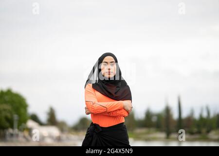 Arab woman wearing headscarf standing with arms crossed outdoors Stock Photo