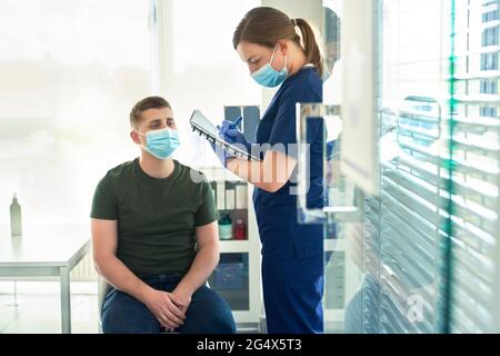 Doctor taking patient's interview before giving COVID-19 vaccine at vaccination center Stock Photo