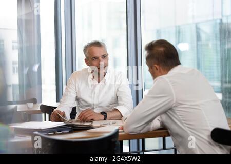 Male entrepreneurs discussing over documents at desk in office Stock Photo