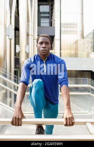 Handsome man doing stretching exercise at railing Stock Photo