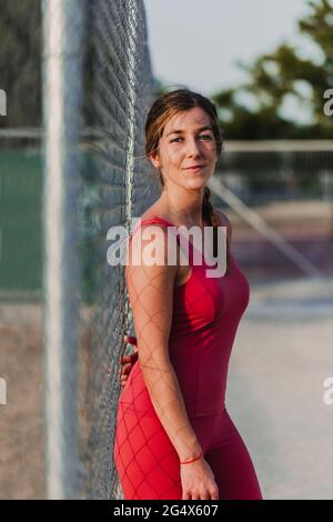 Female athlete in front of fence standing in stadium Stock Photo
