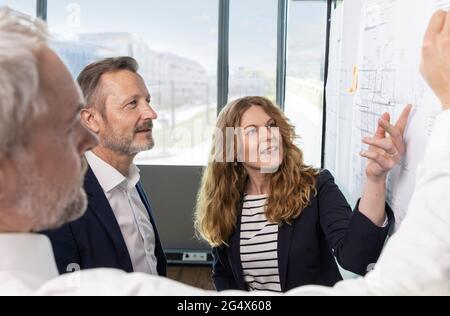 Male and female design professionals discussing over blueprint in office Stock Photo