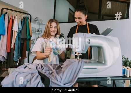 Smiling fashion designers looking at cloths at workshop Stock Photo