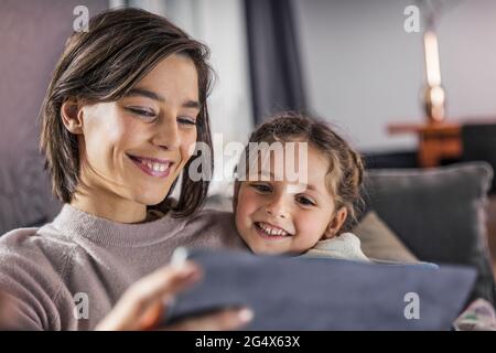 Smiling mother and daughter using digital tablet at home Stock Photo