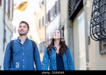 Smiling couple looking away while standing at city street Stock Photo