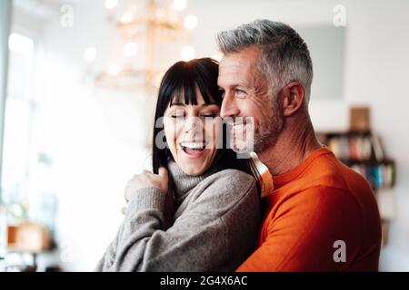 Smiling man embracing woman while looking away at cafe Stock Photo
