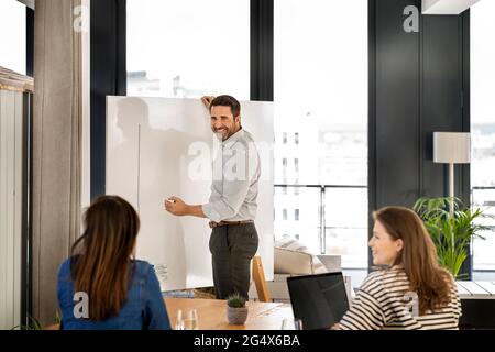 Smiling businessman talking with female colleagues during meeting at office Stock Photo