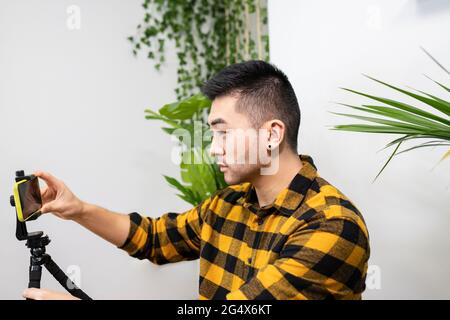 Male professional adjusting smart phone on tripod in office Stock Photo
