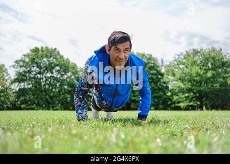 Man doing push-ups while practicing exercise at public park Stock Photo