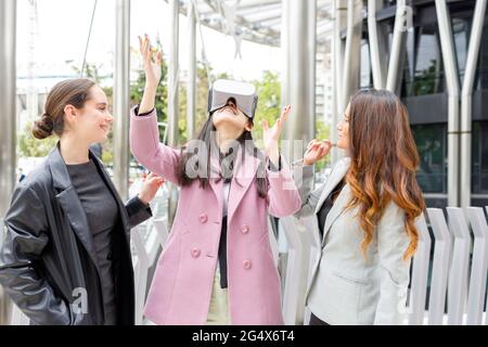 Businesswoman using virtual reality headset while standing by female colleagues Stock Photo