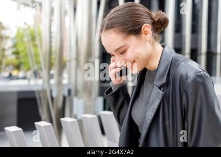 Female entrepreneur smiling while talking on mobile phone Stock Photo