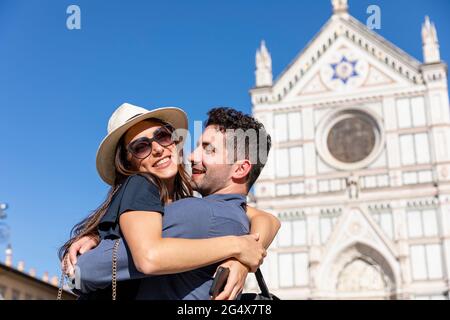 Couple embracing each other on sunny day with Basilica Of Santa Croce in background Stock Photo