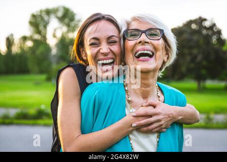 Cheerful granddaughter embracing grandmother from behind at park Stock Photo
