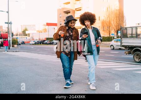 Young women using mobile phone while walking on phone Stock Photo