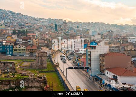 Vehicles on street amidst buildings and The Ancient Agora in Konak during sunset, Smyrna, Izmir, Turkey Stock Photo
