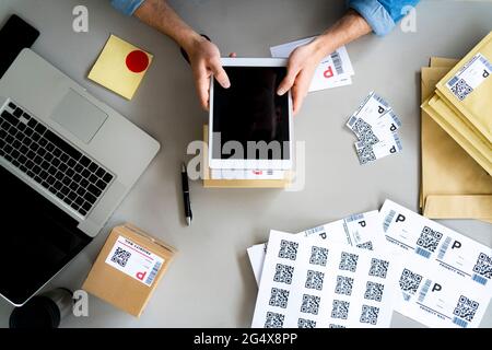 Businessman holding digital tablet over box at desk Stock Photo