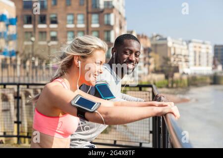 Smiling man and woman leaning on railing while exercising Stock Photo