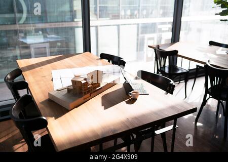 Architectural model and blueprint with laptop on table at office cafeteria Stock Photo