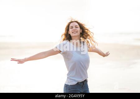 Carefree woman with arms outstretched spinning around at beach