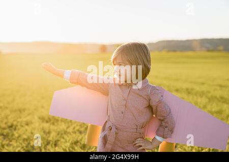 Little girl wearing rocket wings standing with hand on hip looking away Stock Photo