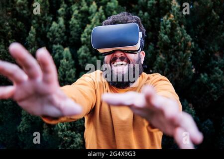 Playful man using VR glasses in garden Stock Photo