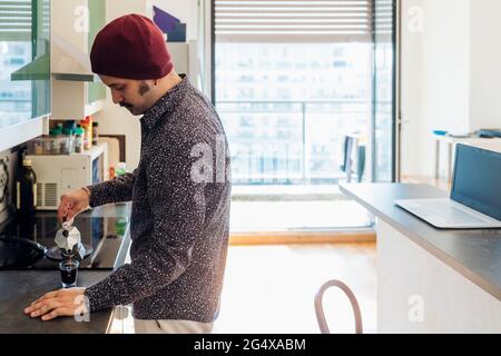Man pouring coffee in cup at kitchen counter Stock Photo