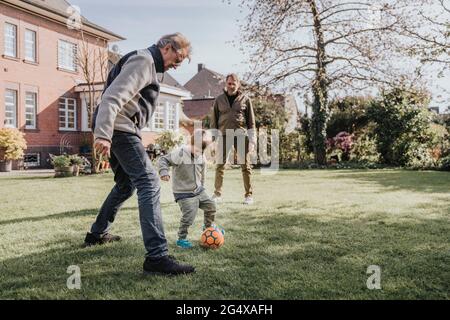 Family playing soccer in backyard Stock Photo