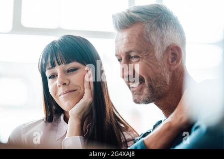 Businesswoman with hand on chin smiling by colleague at cafe Stock Photo