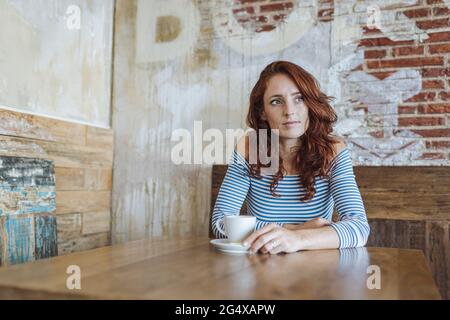 Thoughtful woman looking away while sitting at table in cafe Stock Photo