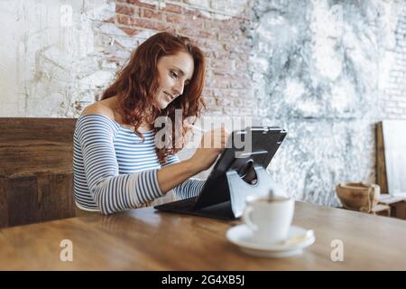 Female graphic designer using tablet while sitting at cafe Stock Photo