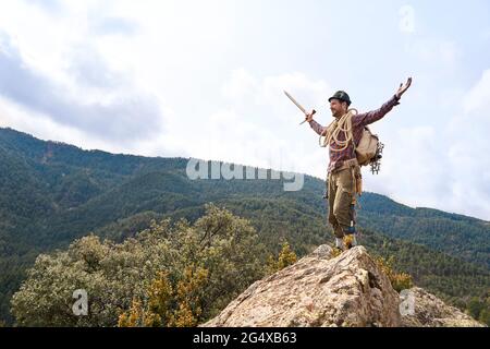 Carefree male tourist standing with arms outstretched on mountain Stock Photo
