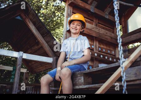 Thoughtful boy in yellow hat sitting in wooden house Stock Photo