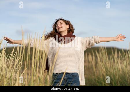Carefree woman with eye closed standing in dunes during vacations Stock Photo