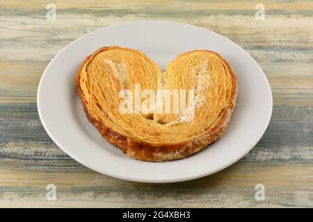 Puff pastry palmeras cookie biscuit topped with sweet sugar glaze on white snack plate Stock Photo