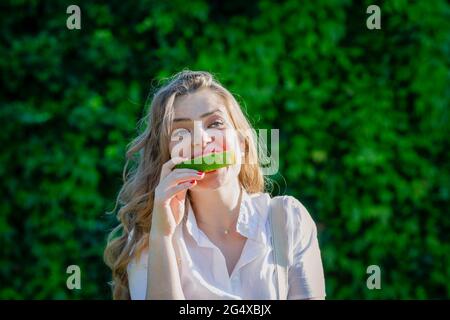 Young woman eating watermelon at garden on sunny day Stock Photo