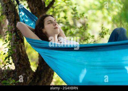Young woman with eyes closed relaxing on hammock Stock Photo