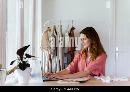 Female fashion designer using laptop while working at home Stock Photo