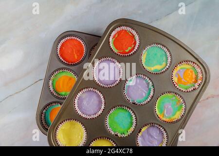 Unbaked rainbow cupcakes on oven tray. Top view. Stock Photo