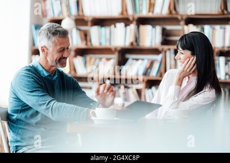Smiling male owner using digital tablet by female colleague in coffee shop Stock Photo