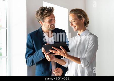 Smiling colleagues using digital tablet while working at office Stock Photo