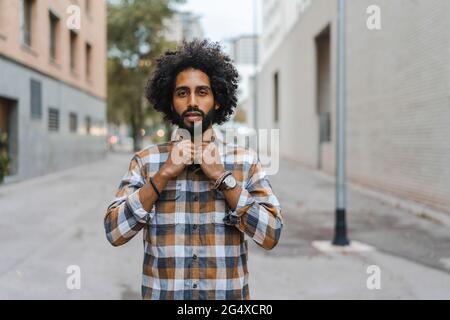 Man buttoning shirt while standing on footpath Stock Photo